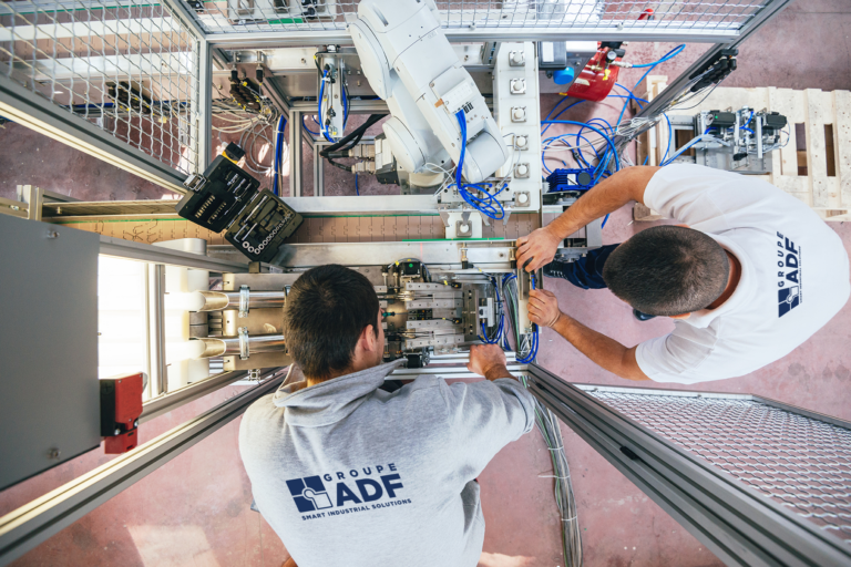 Top view image: 2 men with polo shirts working on electrical equipment - ADF company illustration