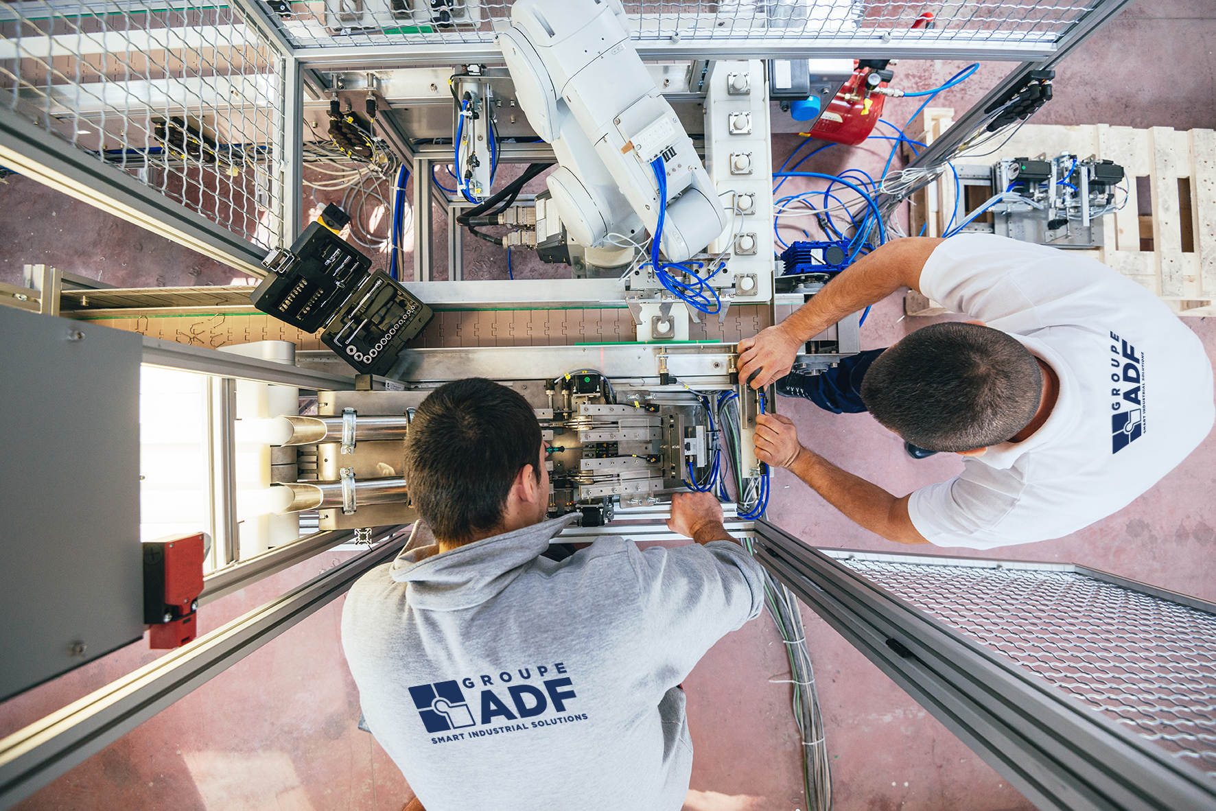 Image vue de dessus : 2 hommes avec polos travaillant sur du matériel électrique - illustration société ADF